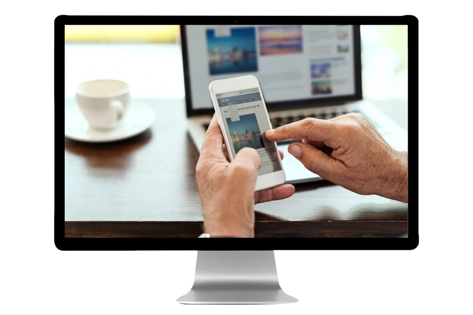 Hands using smartphone with news article, laptop background, modern office setting.