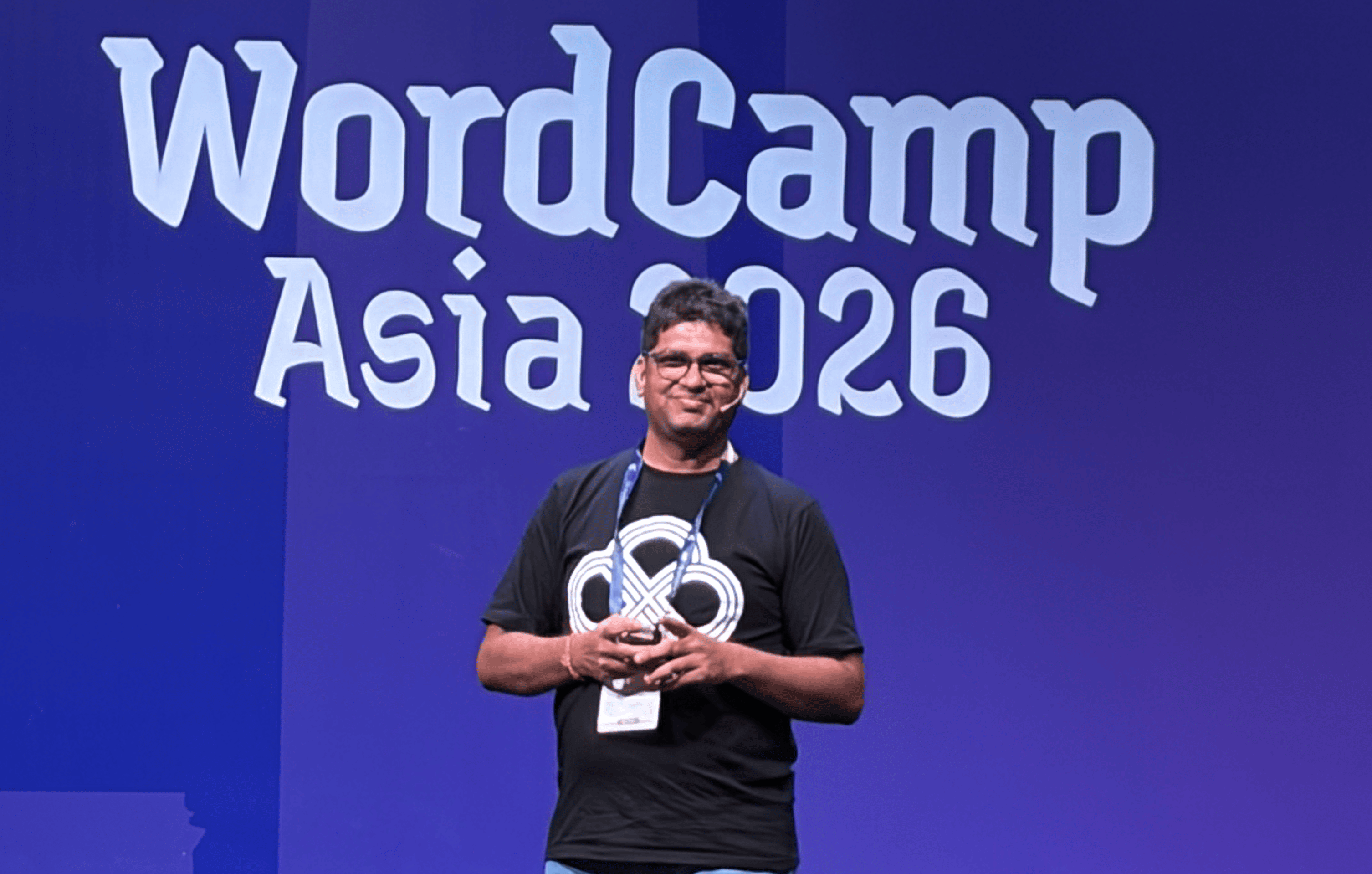 Man smiling onstage at WordCamp Asia 2026, wearing a black shirt.
