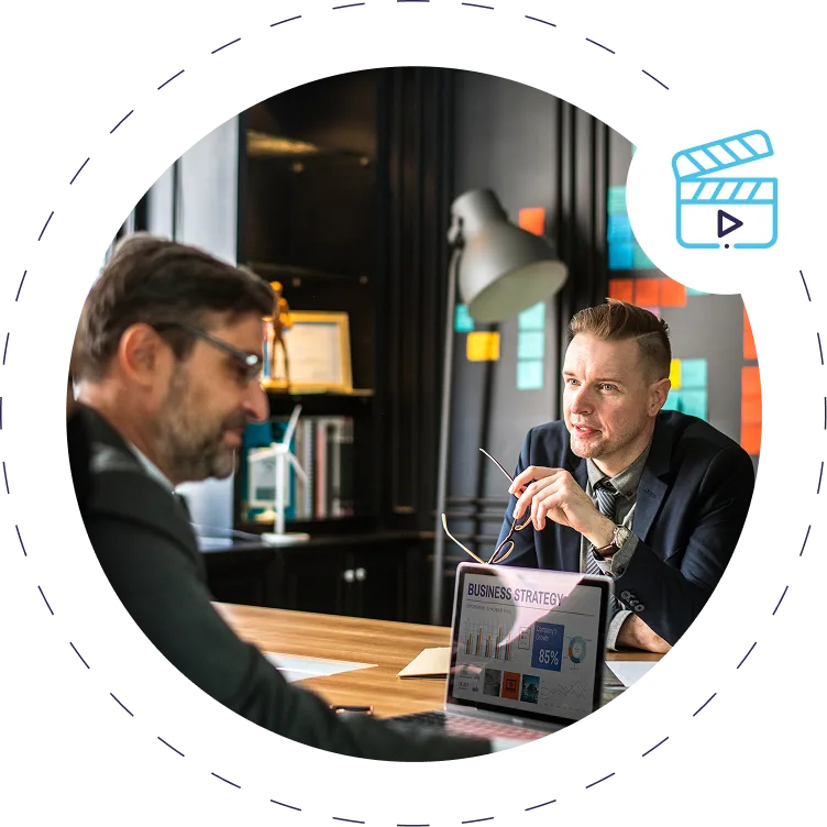 two-men-discussing-business-strategy-laptop-displaying-graphs-in-office-setting Two men discussing business strategy, laptop displaying graphs, in office setting.